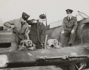 Royal Air Force, loading shells on the four-cannon Hawker Hurricane, December 1941. Two groundcrew members load the shell belts into the cannons while a Flight Lieutenant with the RAF Pilot brevet on his left breast observes. Photos often contain useful clues, like patches and badges, to help with researching WWII ancestors. © Hulton Archive/Getty Images