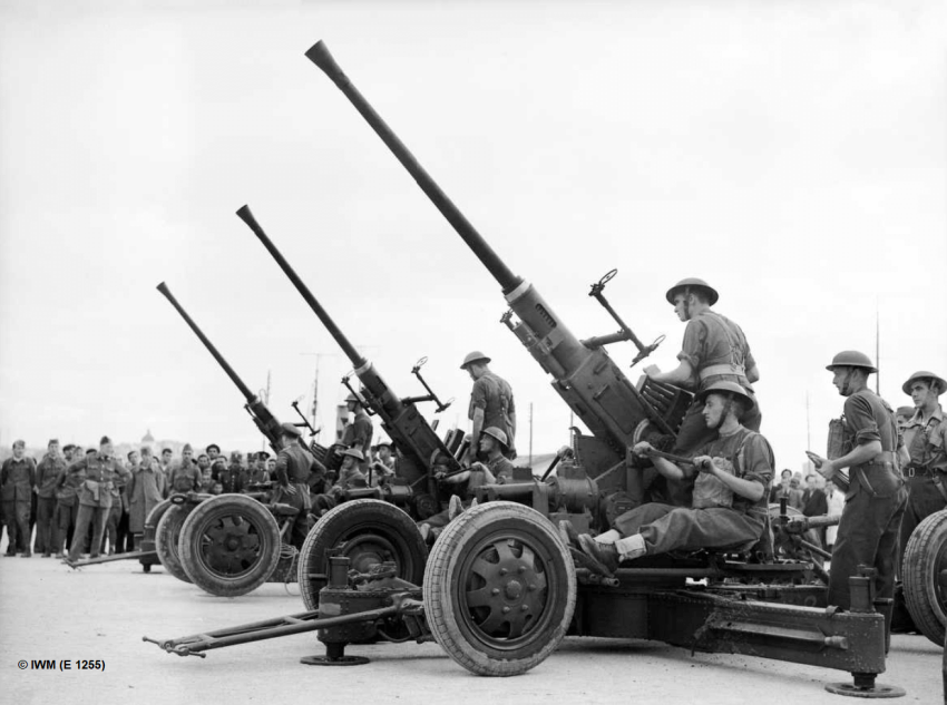 Royal Artillery 40mm Bofors Guns Being Assembled on Their Arrival in Greece 25 November 1940. The crew assemble three guns while a crowd of Greek civilians and military looks on. It is likely that the crew appear in the Royal Artillery Tracer Cards.