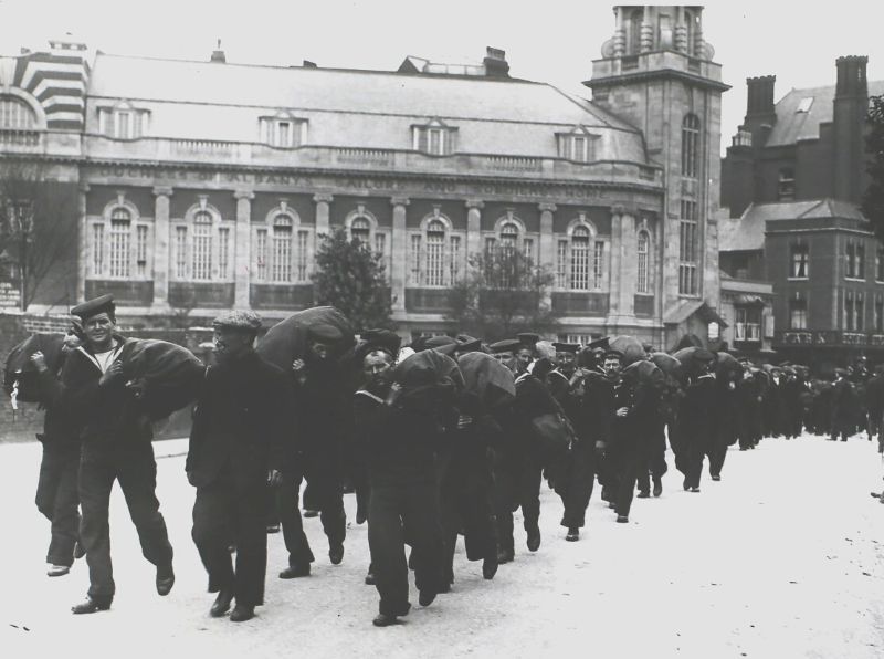 The image shows Naval Reserve men marching through Portsmouth in August 1914. The men are wearing uniforms and carrying their kit over their shoulders, marching in a line. Photos are a useful source for researching navy ancestors. © Hulton Archive/Getty Images