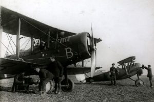 A Royal Flying Corps de Havilland day bomber, February 1918; the kind of plane a Canadian airman may have flown in during WWI. The pilot is seated in the aircraft while three groundcrew load bombs to the underwing. In the background is a Nieuport single-seater fighter plane. ©Hulton Archive/Getty Images