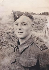 Photo of John Merritt Wentworth in British Army uniform. John is looking at the camera, and his East Surrey Regiment patch is visible on his shoulder. Image provided by Rob P. 